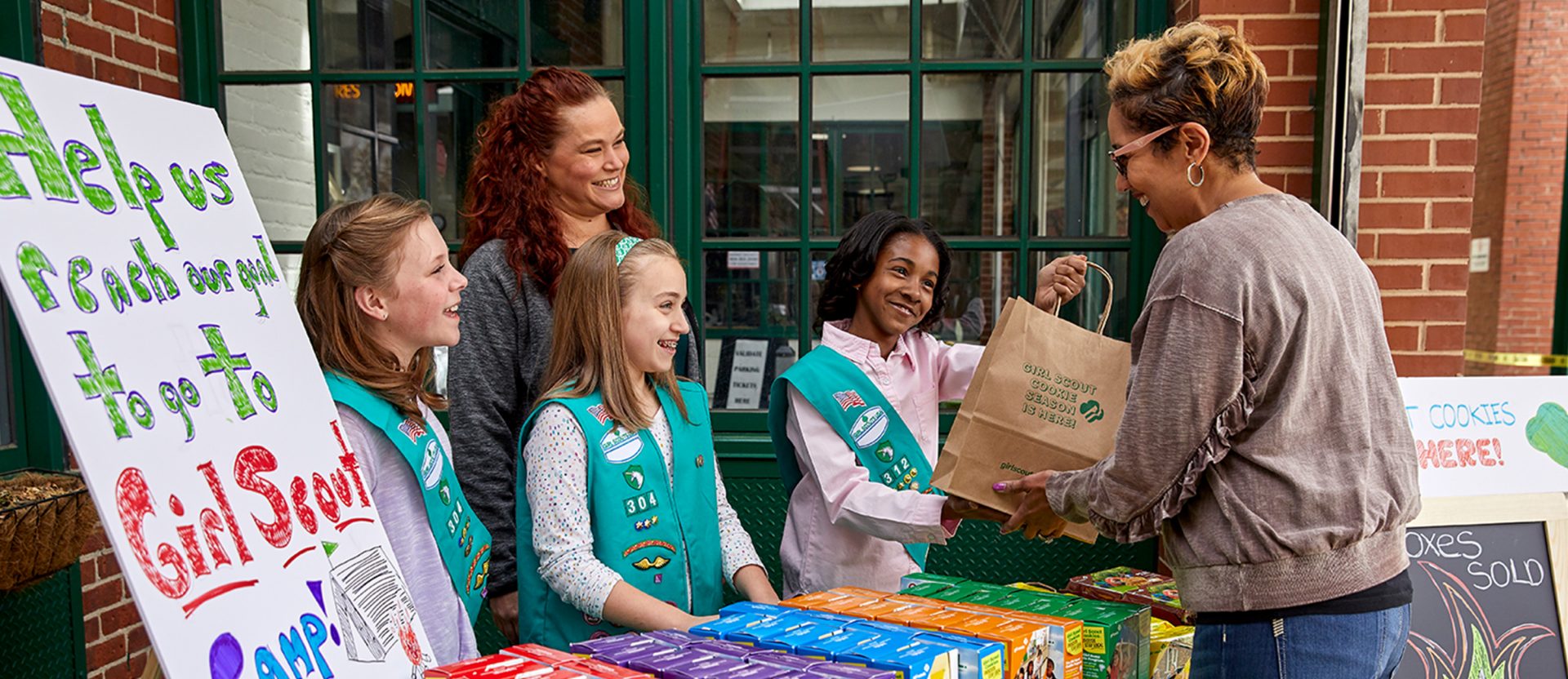 A troop selling cookies to a customer at a booth